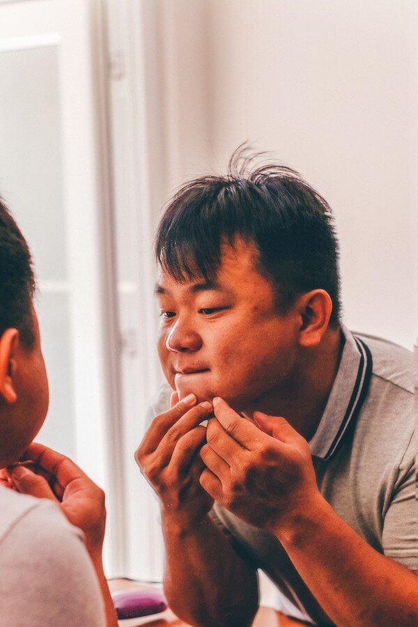 Boy Squeezing Pimple on His Chin